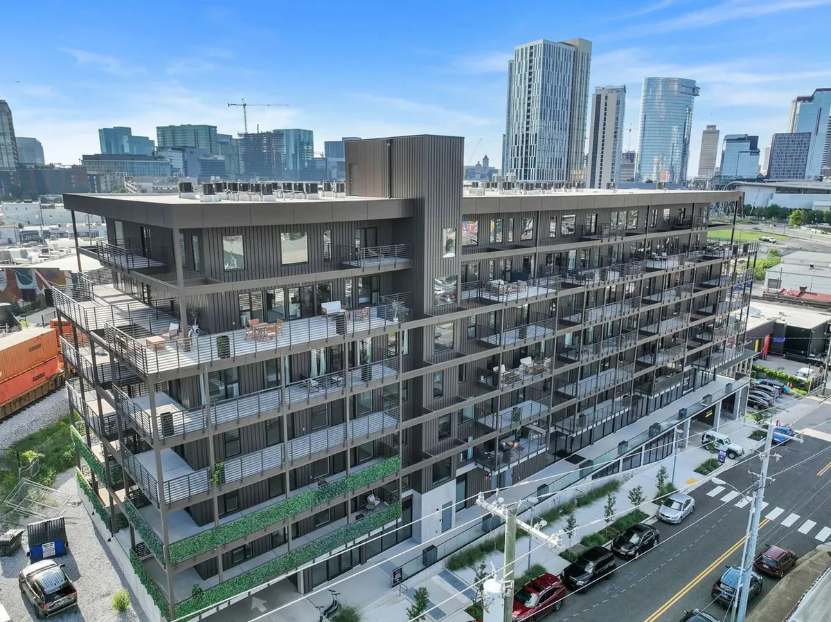 A modern multi-story building with lush rooftop amenities and greenery, featuring inviting terraces and balconies that hint at exclusive resident spaces. The architecture reflects a vibrant, central, and upscale urban lifestyle.