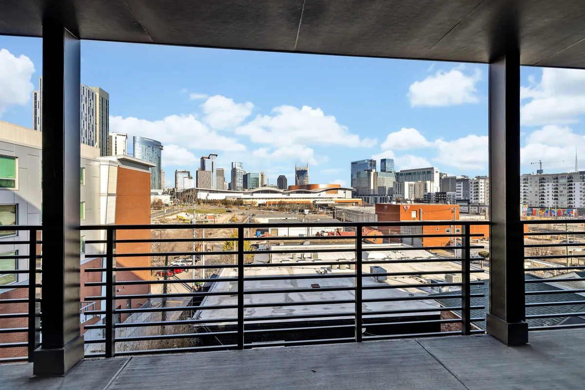 A contemplative city view from a balcony railing at dusk, capturing the expanse of the city skyline and the ambient glow of sunset. The scene is peaceful yet vibrant, reflecting both the tranquility and energy of city life as observed from a private perch.